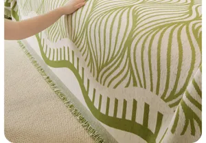 Vista dettagliata della coperta copridivano in stile retrò con motivo verde e texture a frange.