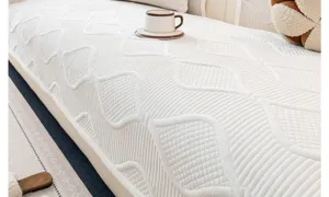 Détail en gros plan d'une housse de canapé en peluche blanche douce au motif géométrique matelassé.