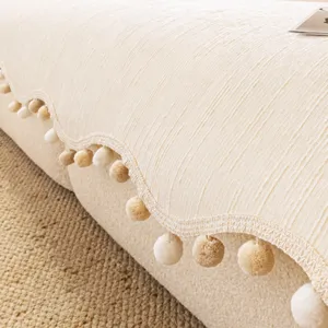 Housse de canapé chenille épaisse avec bord ondulé irrégulier et pompons pour salon.