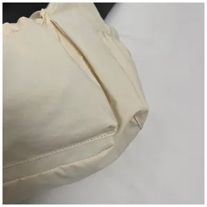 Gedetailleerd overzicht van casual nylon schoudertas in crèmewit met gerimpeld ontwerp.