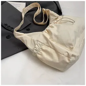 Detailopname van een casual nylon schoudertas in gebroken wit, slouchy design, dagelijkse stijl.