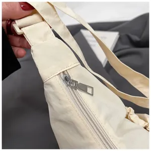 Detailopname van de casual beige nylon schoudertas, met duidelijke weergave van rits en schouderband.