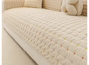 Nahaufnahme von beige gestepptem Chenille Sofakissen mit bunten Punkten, weiche Wohnzimmeroptik.