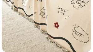 Gedetailleerd uitzicht op gebreide bankdeken met schattig schapenpatroon en kwastjes, zacht textiel.