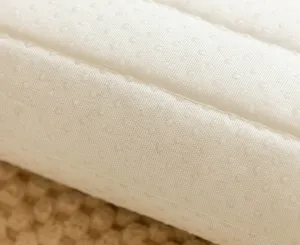 Close-up detail of beige quilted sofa cushion fabric showing anti-slip dots and soft texture.