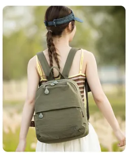 Detail view of casual nylon backpack worn outdoors, showing shoulder straps and zipper design.