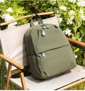Detailed view of the green casual backpack featuring zipper pockets on an outdoor chair.