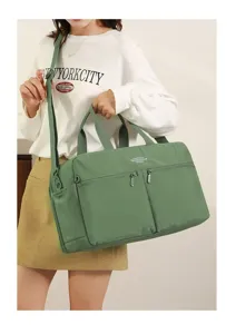 Detail view of the green travel duffel bag showing double zippered pockets and shoulder strap.