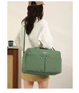 Green travel duffel bag detail view, showing large capacity, zipper pockets and shoulder strap.