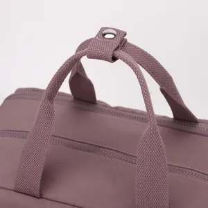 Close up view of the durable purple travel backpack top handle and metal snap button detail.