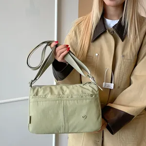 Lightweight multi-layer green crossbody bag detail shot, showing casual storage and strap.