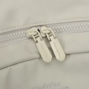 Backpack detail shot showing durable nylon fabric, double zippers, and brand logo embroidery.