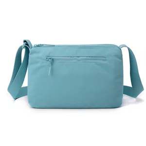 Lightweight nylon crossbody bag detail, multi-layer zipper shoulder bag, casual light blue.
