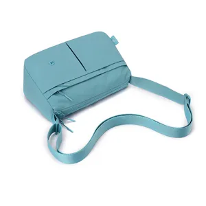 Detail shot of light blue multi-layer crossbody bag featuring functional zipper pockets and strap.
