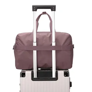 Detail view of purple travel duffel bag mounted on luggage trolley handle securely.