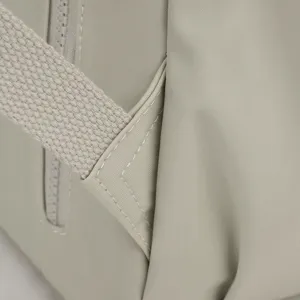 Close-up detail of grey nylon backpack strap, showing fine stitching and durable fabric texture.