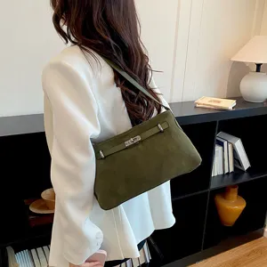 Detail view of the elegant green suede shoulder bag featuring a metallic turn-lock closure and slim strap.