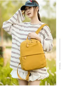 Yellow casual backpack detail showing front zipper pocket and smooth fabric texture.