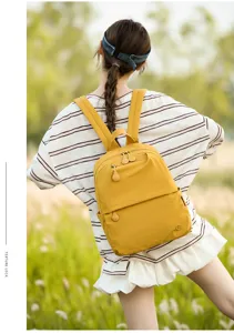 Outdoor detail view of casual yellow backpack worn by model, showing zipper and fabric texture.