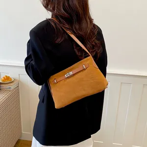 Brown suede shoulder bag detail, elegant metal turn-lock closure, daily commuter style.
