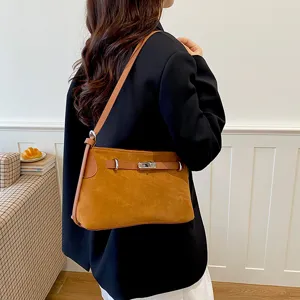 Close-up of stylish brown suede shoulder bag with metal lock detail, perfect for daily commuting.