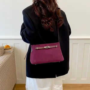 Detail view of dark purple suede shoulder bag with metal lock closure and stylish strap.