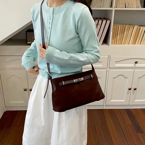 Chic brown suede shoulder bag with metal turn-lock closure, elegant everyday accessory.
