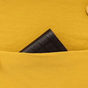 Close-up view of backpack front pocket design with dark textured leather accessory detail.
