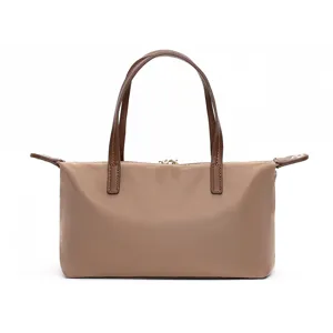 Waterproof nylon detail view of mini shoulder bag with brown leather handles and smooth zipper.