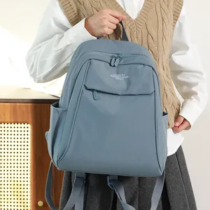 Detail shot of blue nylon backpack featuring front zip pocket and durable straps for daily use.