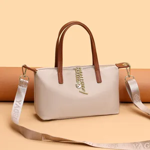 Detail shot of the stylish nylon crossbody handbag, featuring brown handles and metallic chain.