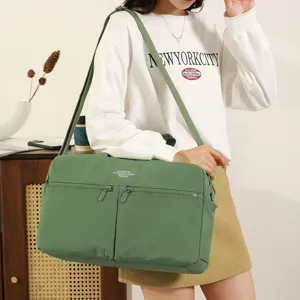 Green travel gym bag detail showing dual front zipper pockets and adjustable shoulder strap.