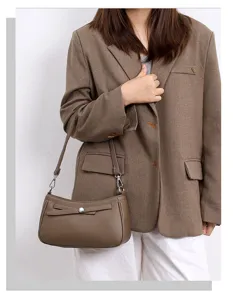 Detail view of stylish brown leather shoulder bag with chic metal buckle and adjustable strap.
