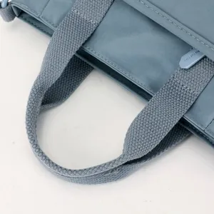 Gros plan détaillé de la poignée de sac à bandoulière en nylon bleu et fermeture.