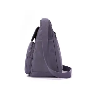 Detail view of a grey nylon crossbody bag showing the side profile and multi-pocket design.