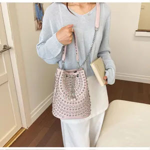 Detail view of the pink litchi grain studded bucket bag featuring metallic chain and pearl accents.