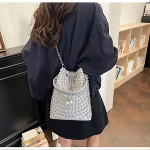 Detailed view of the gray studded bucket bag with chain strap and punk style elements.