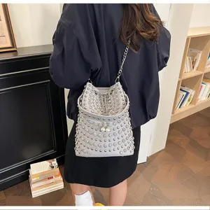 Detailed view of the stylish leather studded bucket bag featuring chic chain straps and pearls.