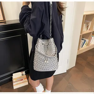 Close-up of the grey studded bucket bag featuring metal chain and pearl drawstring details.