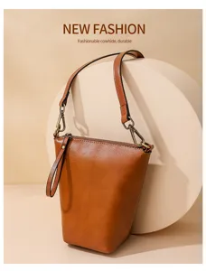 Brown leather shoulder bag detail showing cowhide texture, metal hardware and zipper closure.