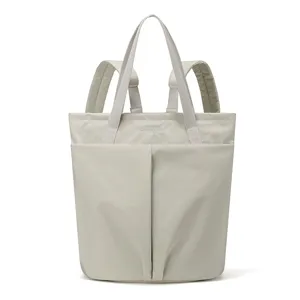 Detailed view of the lightweight nylon tote backpack in light gray with dual top handles.