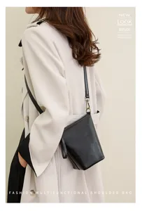 Detail view of a stylish black leather bucket shoulder bag worn in fashion scene.