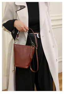 Detailed shot of stylish brown leather bucket shoulder bag with elegant metal hardware.