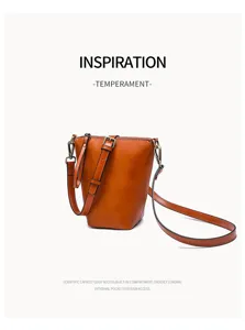 Detailed view of brown leather bucket shoulder bag with adjustable strap and metal hardware.