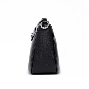 Side detail view of black textured leather crossbody shoulder bag with silver hardware.