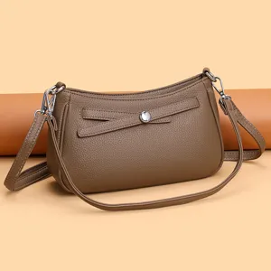 Detail view of brown leather crossbody shoulder bag with metal buckle and bow strap.