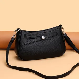 Detail shot of black leather crossbody bag featuring elegant bow decor and metal clasp.