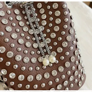 Close-up of brown litchi grain bucket bag with shimmering rhinestones, metal studs and chain.