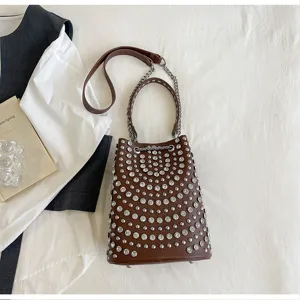 Detailed view of the brown studded bucket bag featuring metallic hardware and chain strap.