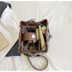 Detail view of brown litchi pattern bucket bag interior, featuring metal chain and inner storage.